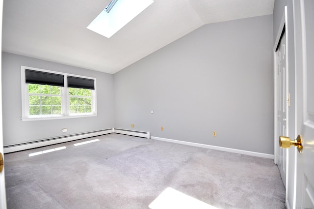 carpeted empty room with vaulted ceiling, a skylight, baseboards, and baseboard heating
