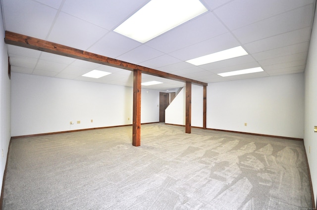 finished below grade area with a paneled ceiling, light colored carpet, and baseboards