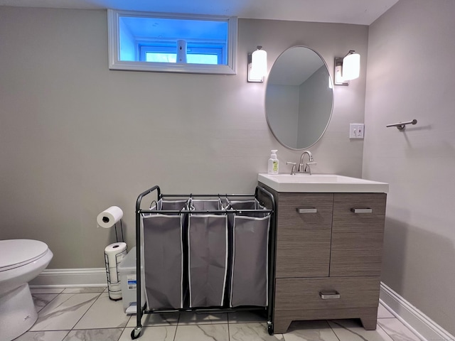 half bath with marble finish floor, vanity, and baseboards