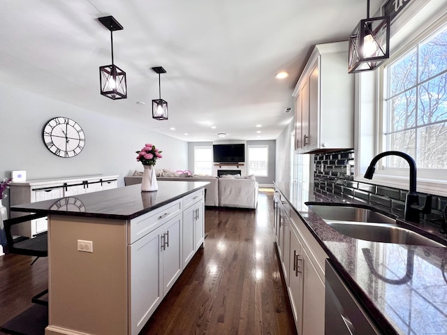 kitchen with tasteful backsplash, dark wood-style floors, a sink, a kitchen bar, and stainless steel dishwasher