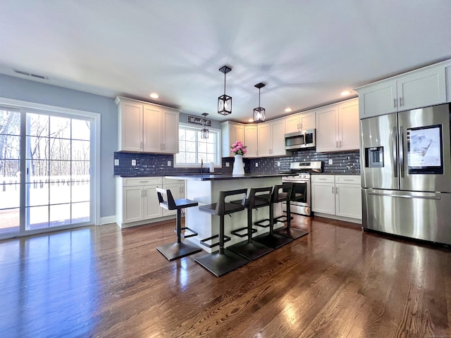 kitchen featuring dark countertops, visible vents, stainless steel appliances, and dark wood finished floors