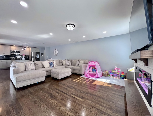 living room with dark wood-style floors and recessed lighting