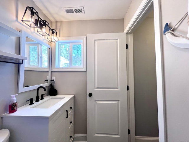 bathroom with toilet, visible vents, and vanity