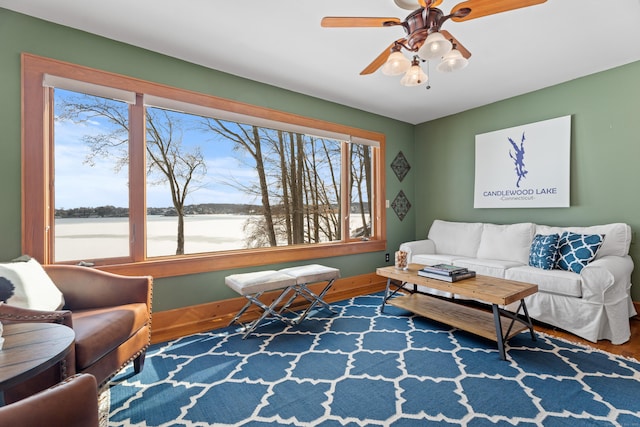 living area featuring a water view, ceiling fan, baseboards, and wood finished floors