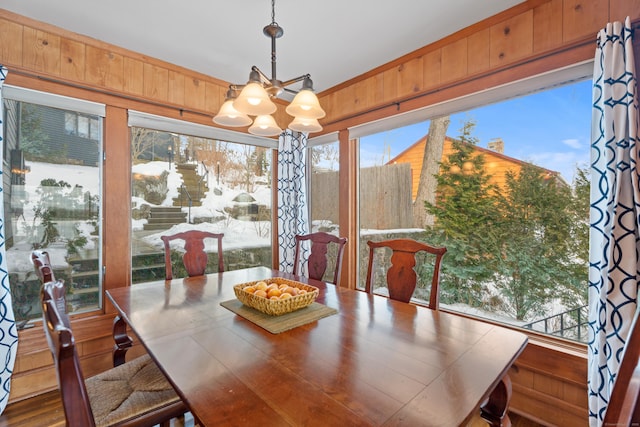 dining area featuring wooden walls and a chandelier