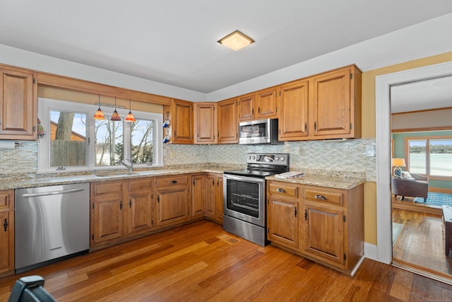 kitchen with a sink, light wood-style flooring, stainless steel appliances, and a wealth of natural light