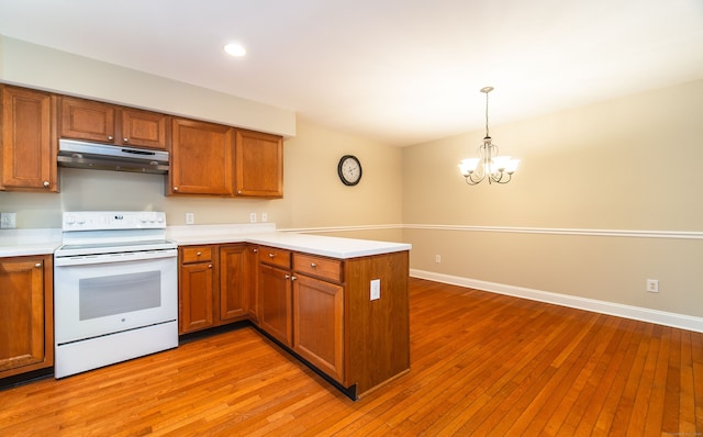 kitchen featuring light wood-style flooring, under cabinet range hood, white electric range, a peninsula, and brown cabinetry