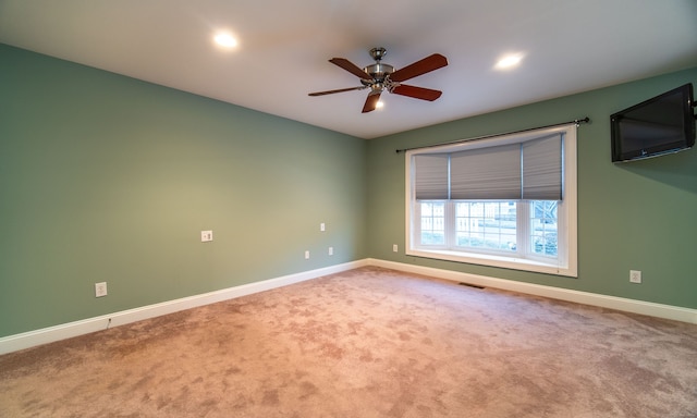 carpeted spare room featuring visible vents, a ceiling fan, and baseboards