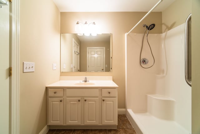 bathroom featuring walk in shower, vanity, and baseboards