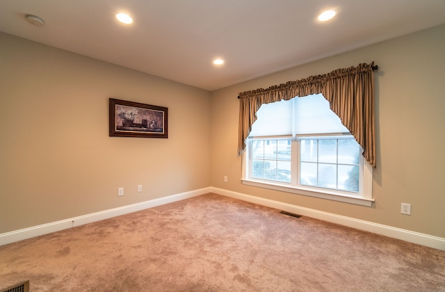 carpeted spare room featuring baseboards, visible vents, and recessed lighting