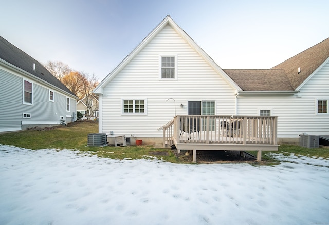 snow covered house with a deck, a shingled roof, and cooling unit