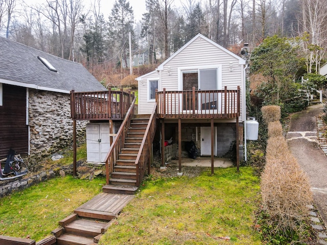 rear view of house with a lawn, a deck, and stairs