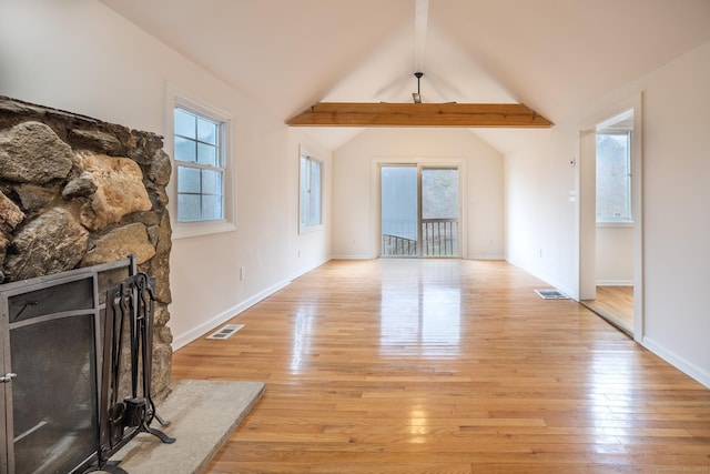 unfurnished living room featuring vaulted ceiling with beams, light wood-style flooring, visible vents, and a stone fireplace