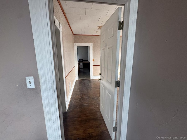 corridor featuring dark wood-type flooring, visible vents, crown molding, and wallpapered walls