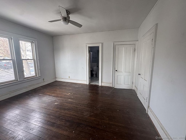 unfurnished bedroom featuring dark wood-style floors, connected bathroom, ceiling fan, and baseboards