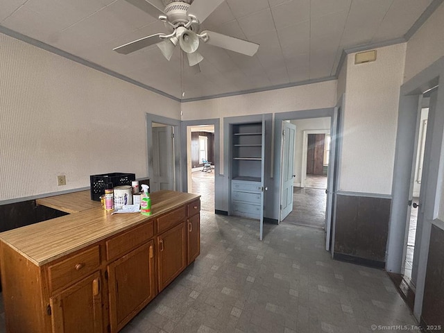 kitchen featuring brown cabinetry, light countertops, ornamental molding, and ceiling fan