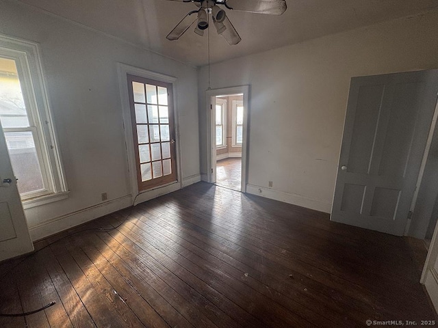 spare room with dark wood-type flooring, baseboards, and a ceiling fan