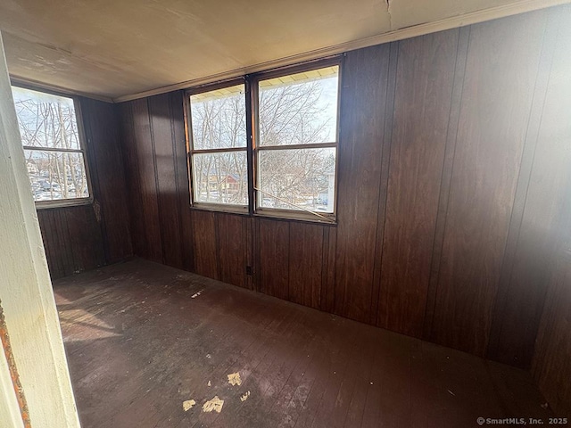 unfurnished room with dark wood-style floors and wood walls