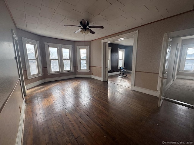 interior space featuring dark wood-style floors, ornamental molding, a ceiling fan, and baseboards