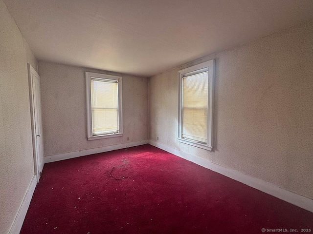 empty room with dark carpet and baseboards