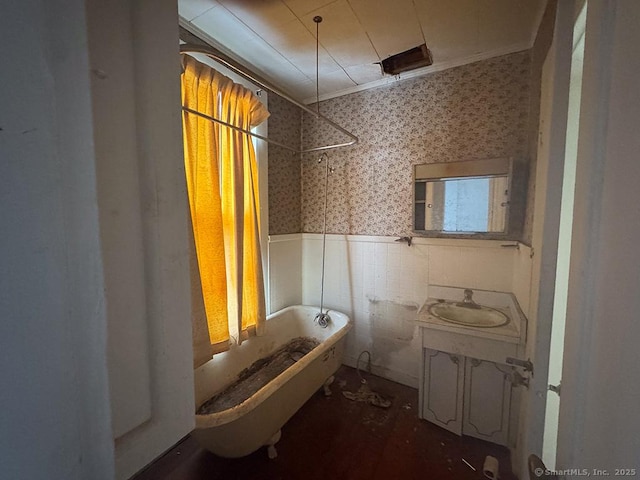 full bath featuring a wainscoted wall, tile walls, vanity, ornamental molding, and wallpapered walls