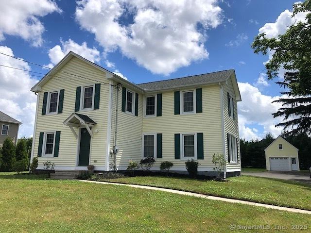 colonial house with an outbuilding, a detached garage, and a front yard