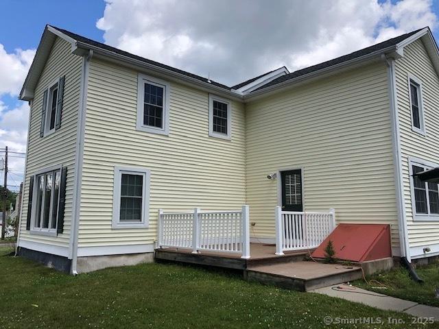 back of property with a lawn and a wooden deck