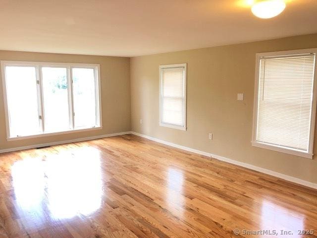 spare room with baseboards and light wood-style floors