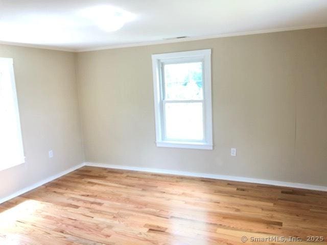 spare room featuring crown molding, baseboards, and wood finished floors