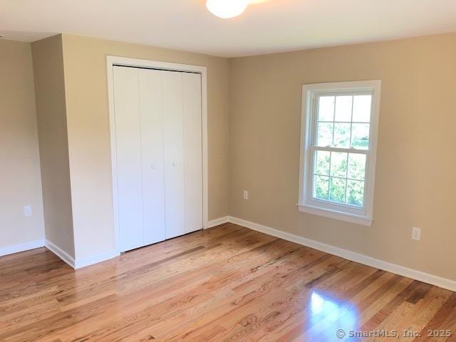 unfurnished bedroom with light wood-style floors, baseboards, and a closet