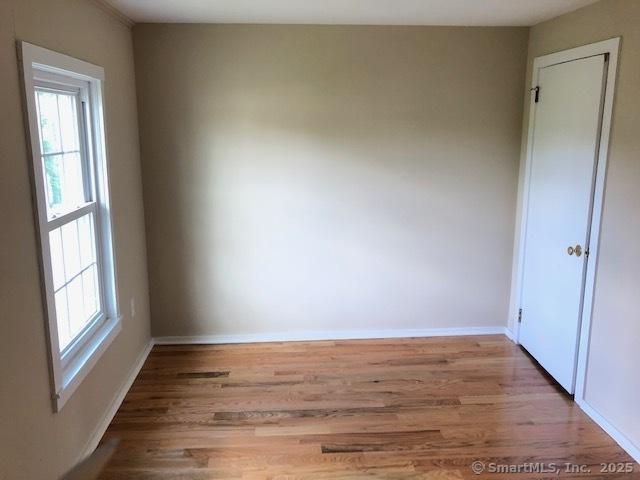 empty room with wood finished floors, baseboards, and a wealth of natural light