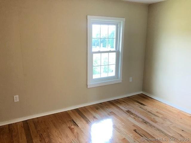 spare room featuring wood finished floors and baseboards