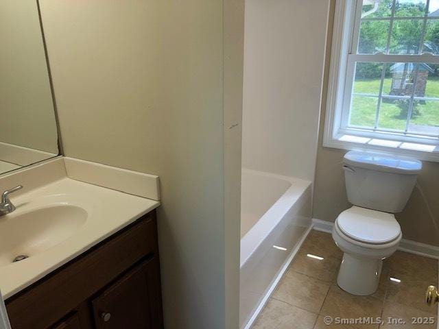 bathroom featuring tile patterned floors, toilet, baseboards, a bathtub, and vanity