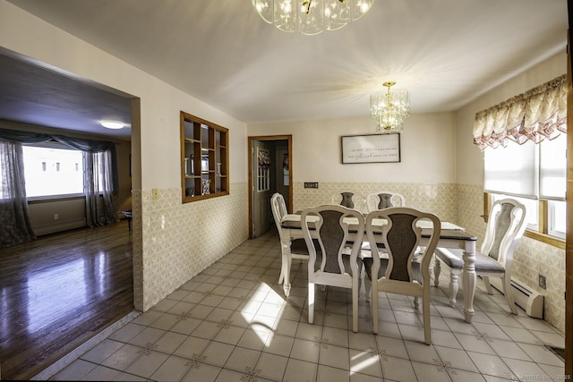 dining room featuring a healthy amount of sunlight, a wainscoted wall, a chandelier, and a baseboard heating unit