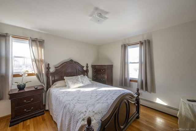 bedroom featuring a baseboard heating unit and light wood finished floors