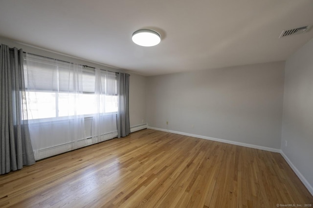 unfurnished room featuring light wood-type flooring, baseboards, visible vents, and baseboard heating