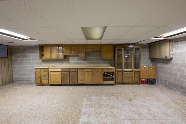 kitchen featuring open shelves, light countertops, brown cabinets, light floors, and glass insert cabinets