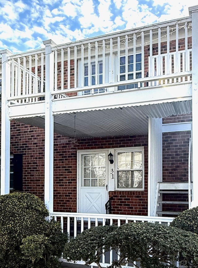 exterior space with a balcony and brick siding