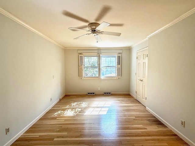 empty room with ornamental molding, light wood finished floors, visible vents, and baseboards