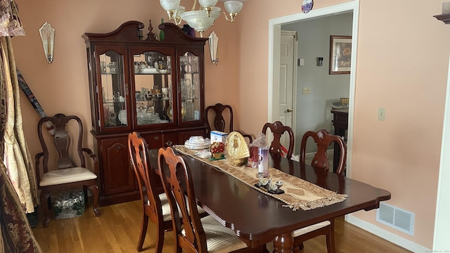 dining area featuring a chandelier, wood finished floors, and visible vents