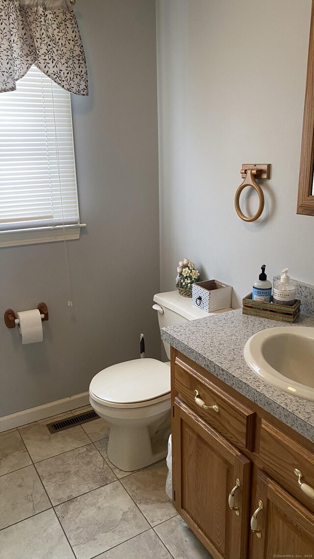 half bathroom with toilet, tile patterned floors, visible vents, and vanity