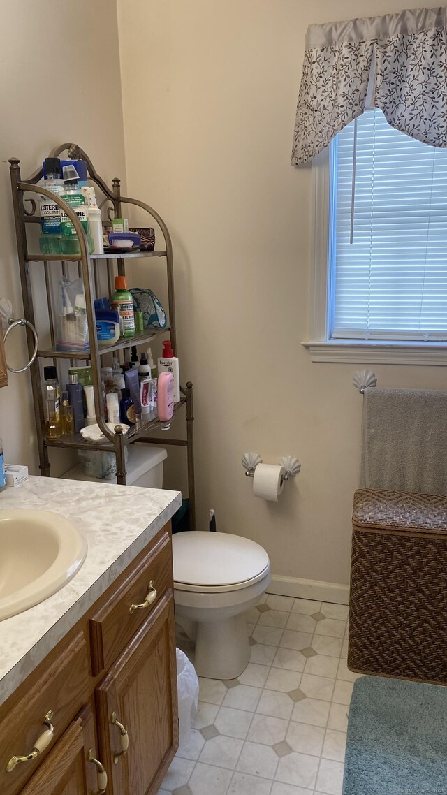 bathroom with toilet, tile patterned floors, baseboards, and vanity