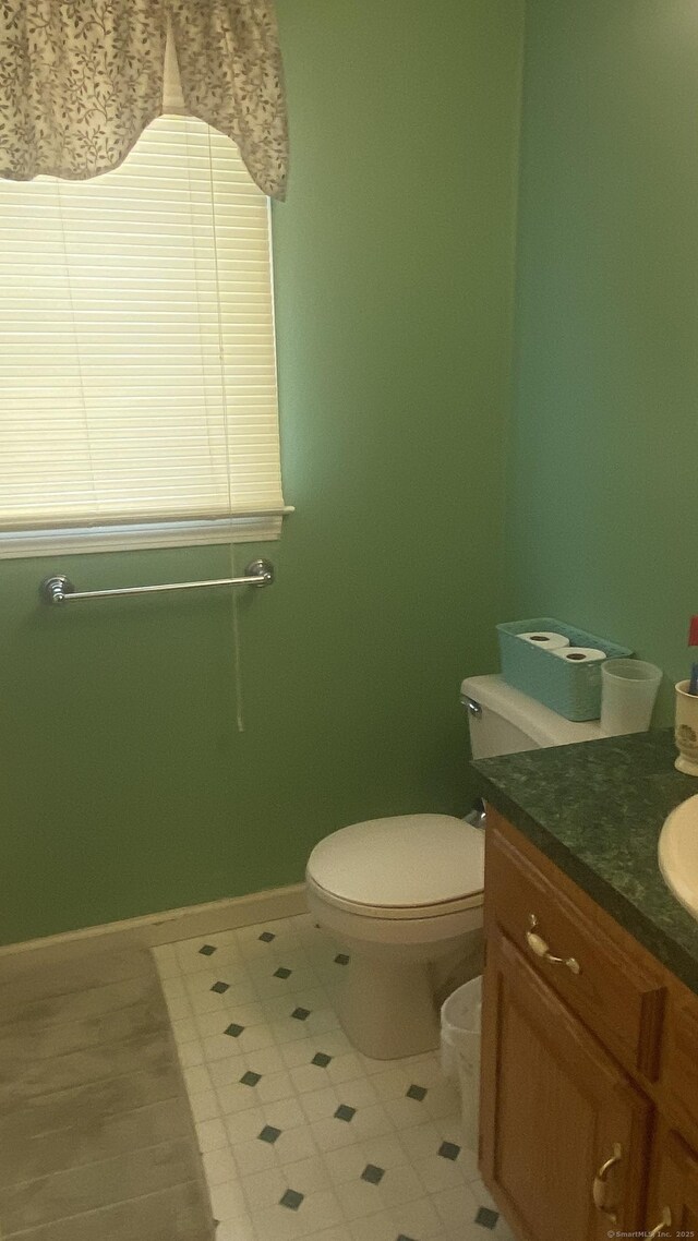 half bath with toilet, vanity, and baseboards