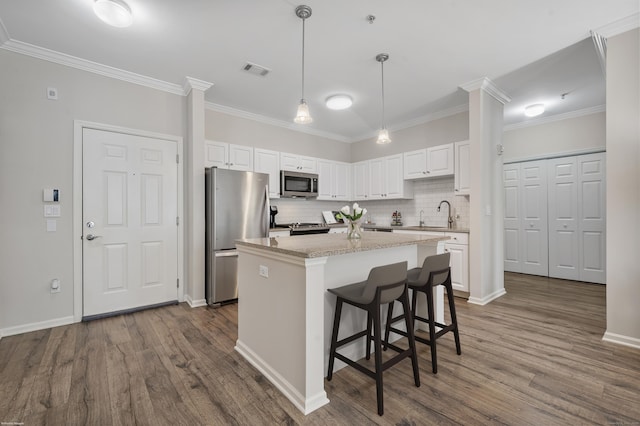 kitchen with white cabinets, light stone countertops, a kitchen island, and stainless steel appliances