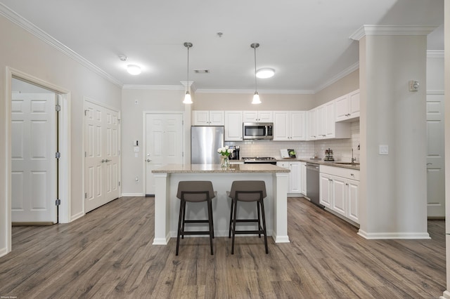 kitchen with a kitchen island, stainless steel appliances, white cabinetry, pendant lighting, and a sink