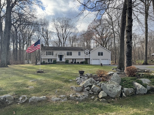 raised ranch with an attached garage, entry steps, and a front yard