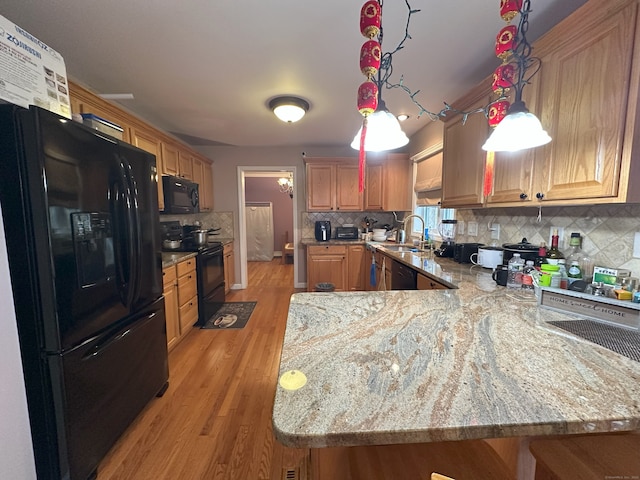 75 Heather Glen Ln, Groton, CT 06355 - kitchen featuring black appliances, a peninsula, light wood-type flooring, tasteful backsplash, and light stone counters