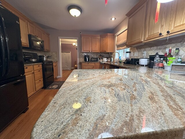 75 Heather Glen Ln, Groton, CT 06355 - kitchen with black appliances, light stone counters, tasteful backsplash, a sink, and light wood-type flooring