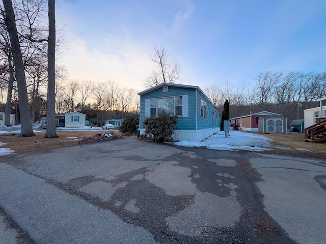 view of front of house featuring aphalt driveway, an outdoor structure, and a shed