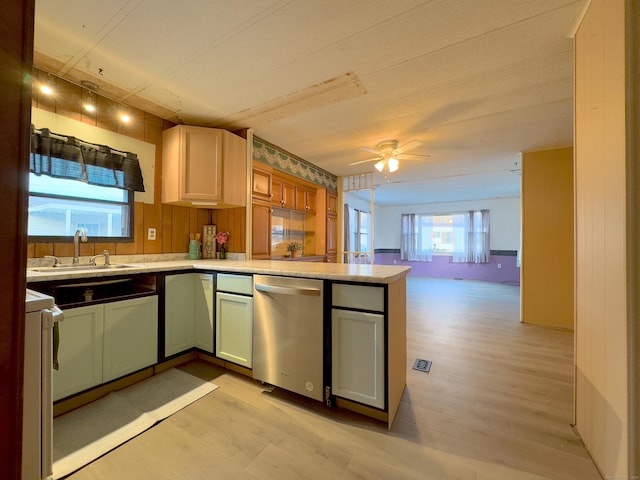 kitchen featuring stainless steel dishwasher, light countertops, a sink, and light wood finished floors